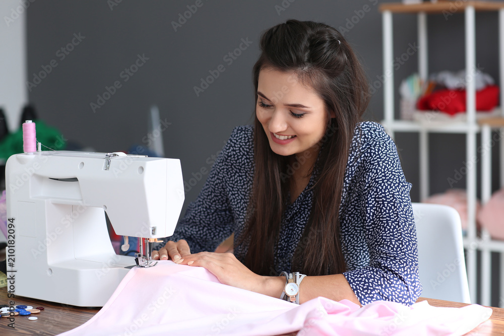 年轻的女裁缝在工作室使用缝纫机
