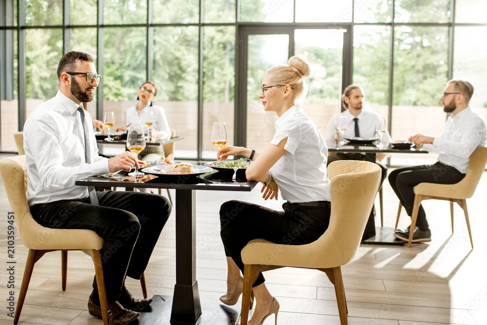 商务人士两人一组坐在现代餐厅享用美味的午餐