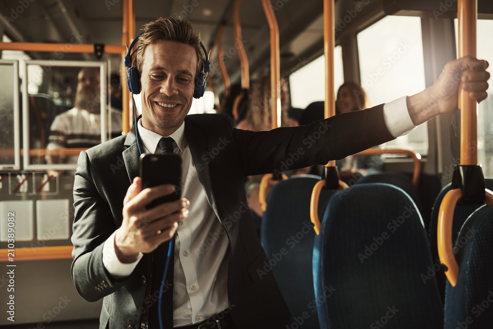 Smiling businessman listening to music while riding on a bus