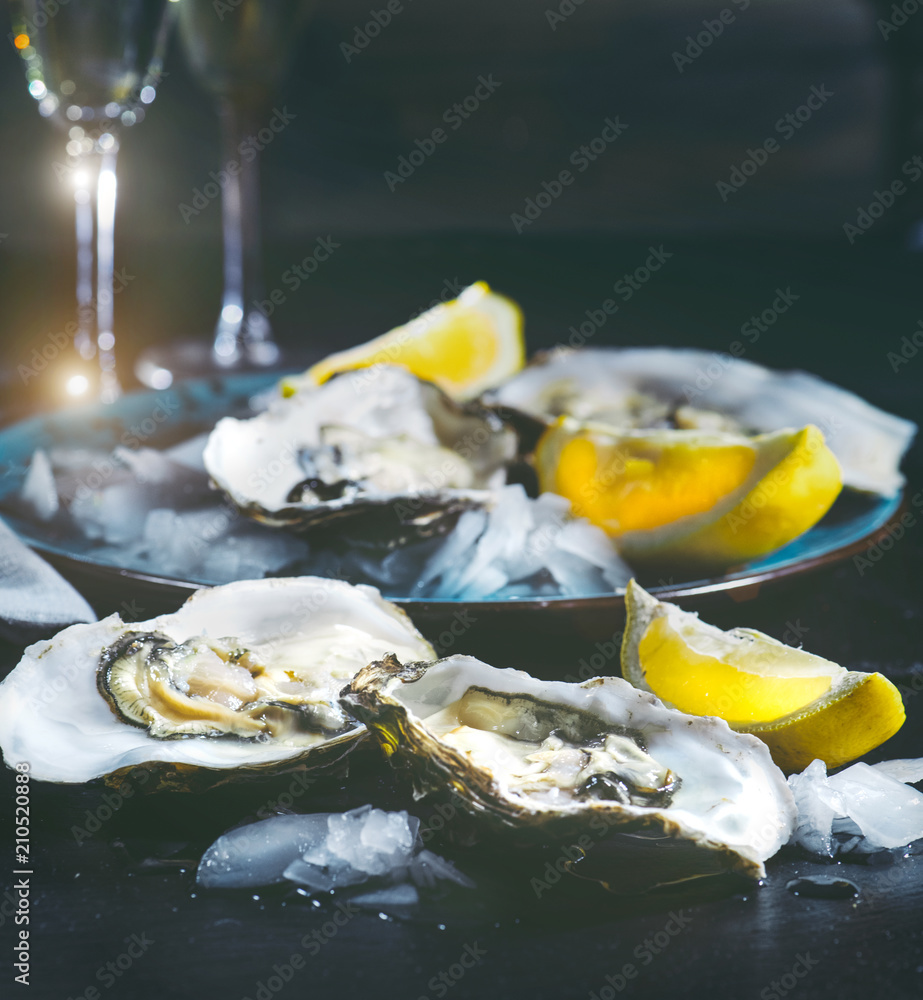 蓝色盘子里的牡蛎特写。餐桌上有新鲜的牡蛎、柠檬和冰块。健康的海鲜。牡蛎