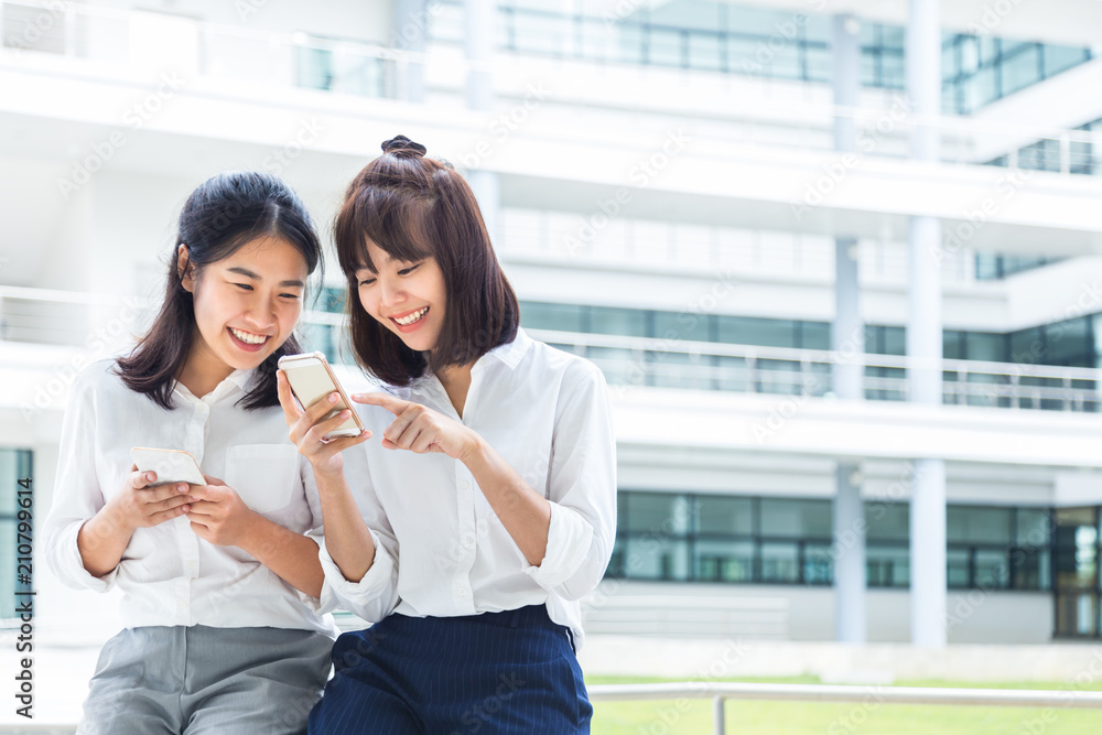 两名年轻的亚洲女性在家中午休时用智能手机享受社交媒体