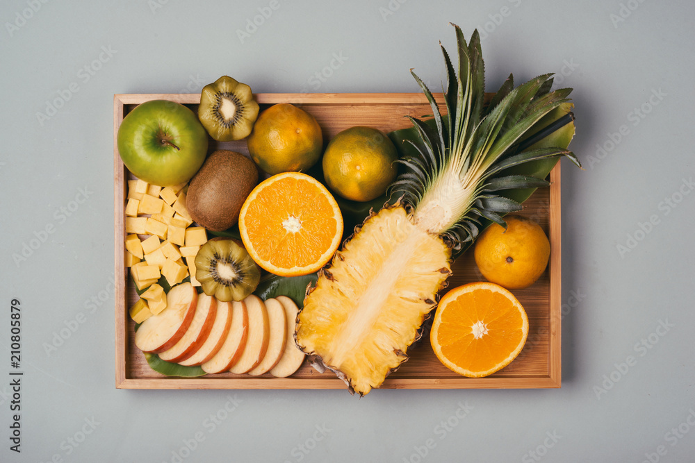 盘子里有各种新鲜水果。木制盘子里有苹果、橙子、猕猴桃、菠萝、橘子。俯视图