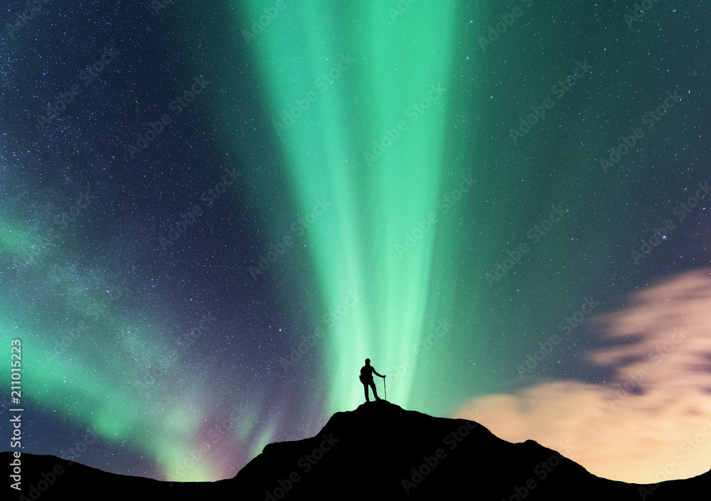 Aurora and silhouette of standing woman on the top of mountain. Lofoten islands, Norway. Aurora bore