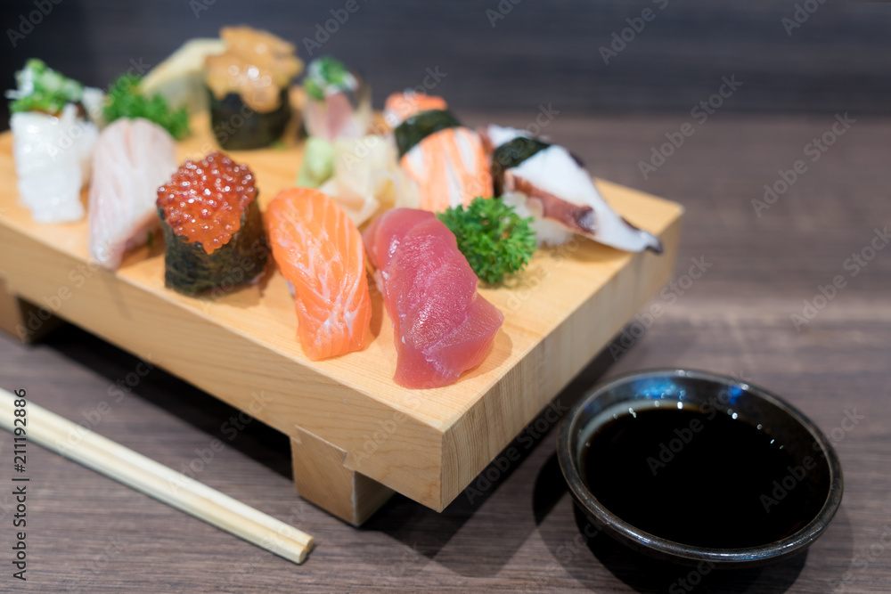 近景寿司和生鱼片混合在黑色木桌上的木板上。日本食物。