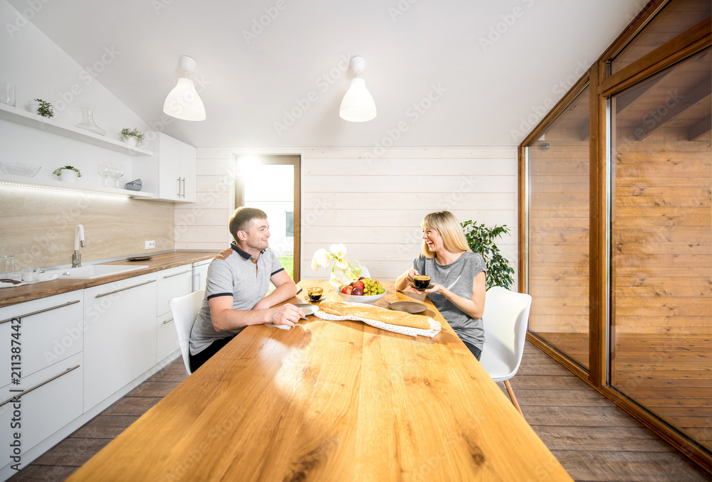年轻幸福的一对夫妇坐在模式餐厅的木桌旁吃早餐