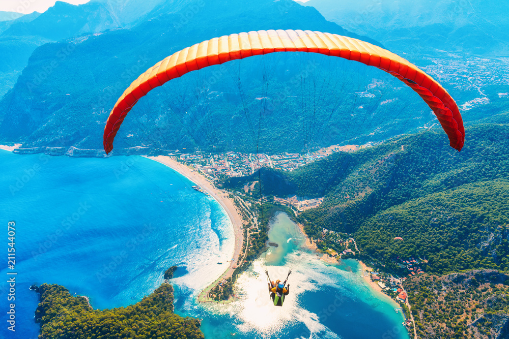 空中滑翔伞。滑翔伞双人组在碧水青山的海面上飞行