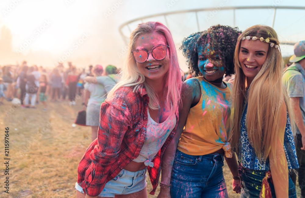 Multiethnic group of friends with colorful powder on clothes and bodies at summer holi festival havi
