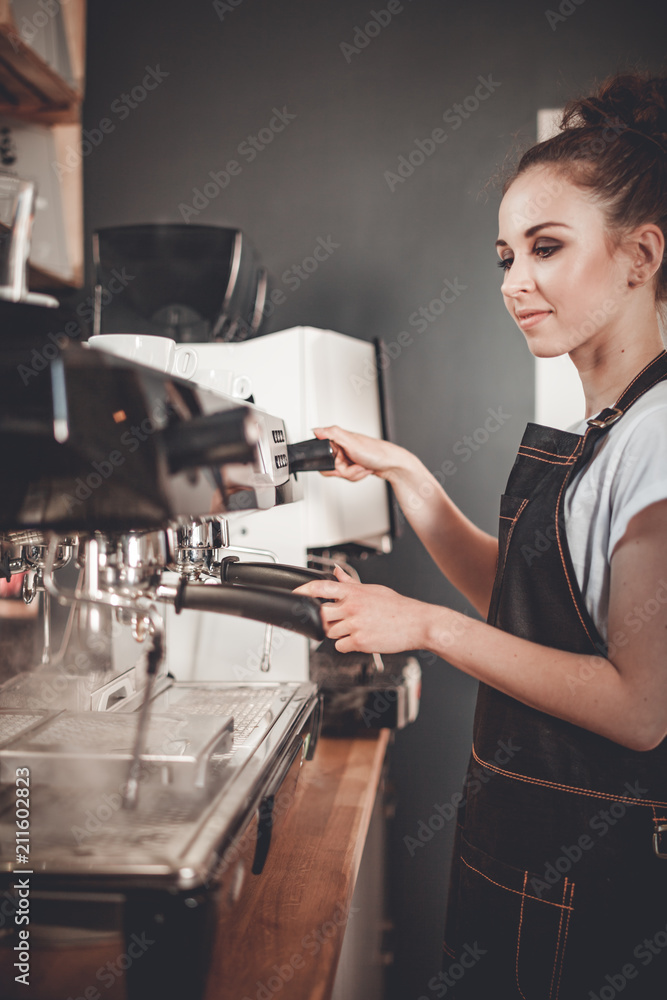 年轻女咖啡师在咖啡馆用机器准备咖啡