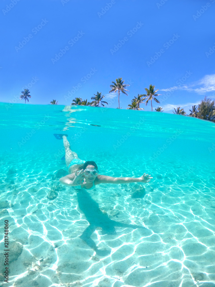 半水下：一名女子朝着镜头浮潜，做出了ok的手势。