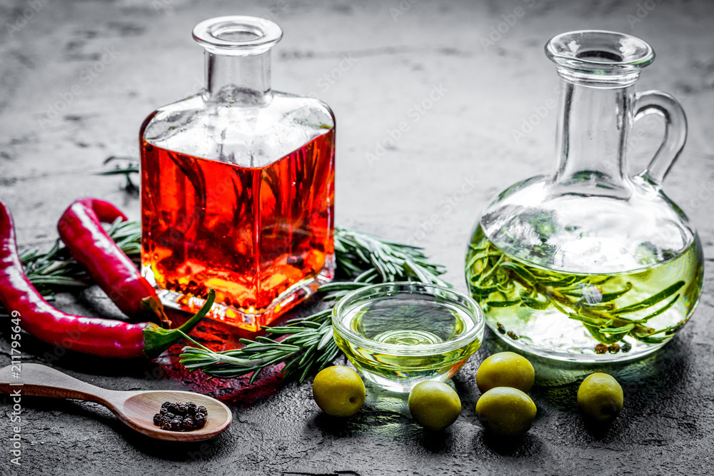 石头背景的辣椒、橄榄油和香草瓶子