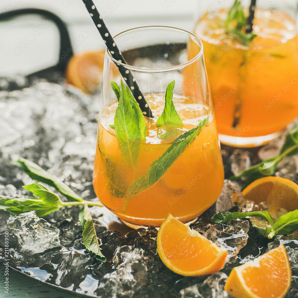 清爽的冷酒精夏季柑橘鸡尾酒，配无柄玻璃杯中的橙子、薄荷和冰块