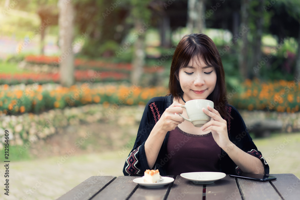 亚洲女性在家里的花园里喝杯咖啡放松身心。