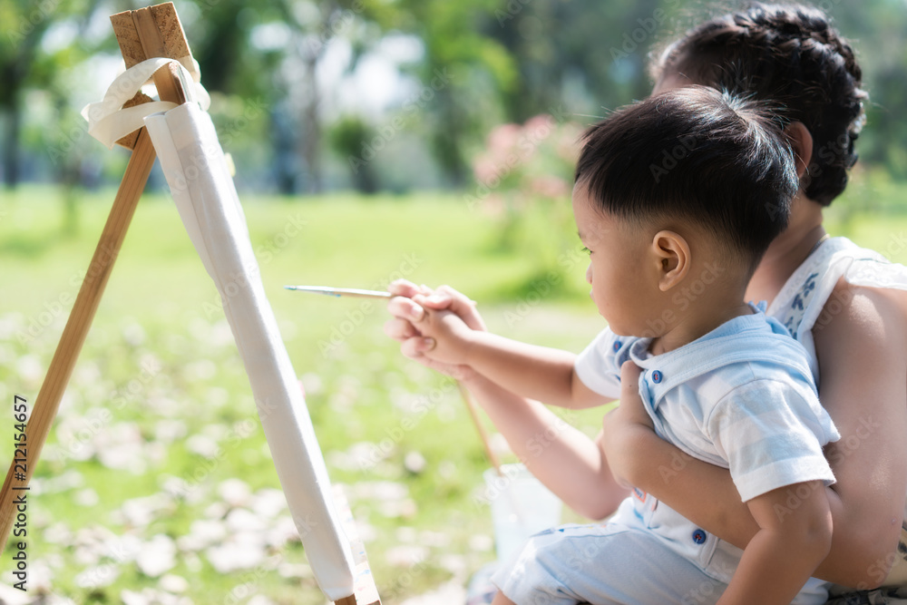 亚洲小男孩和妹妹在公园里一起画画。孩子们画画。孩子和爸爸一起画画
