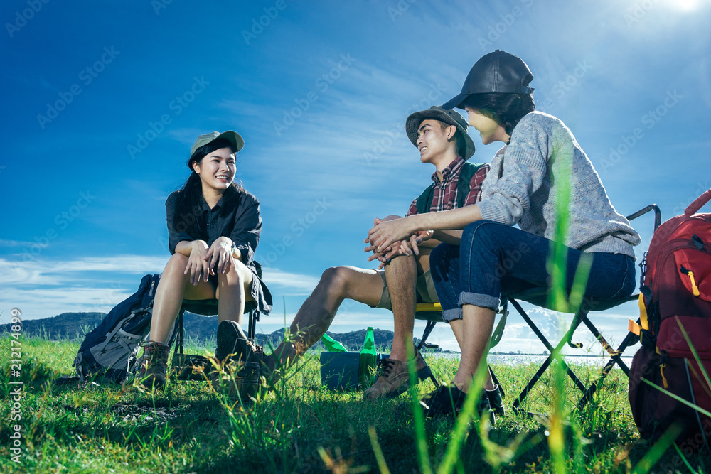 一群亚洲朋友坐在椅子上，在帐篷外一起喝啤酒和水