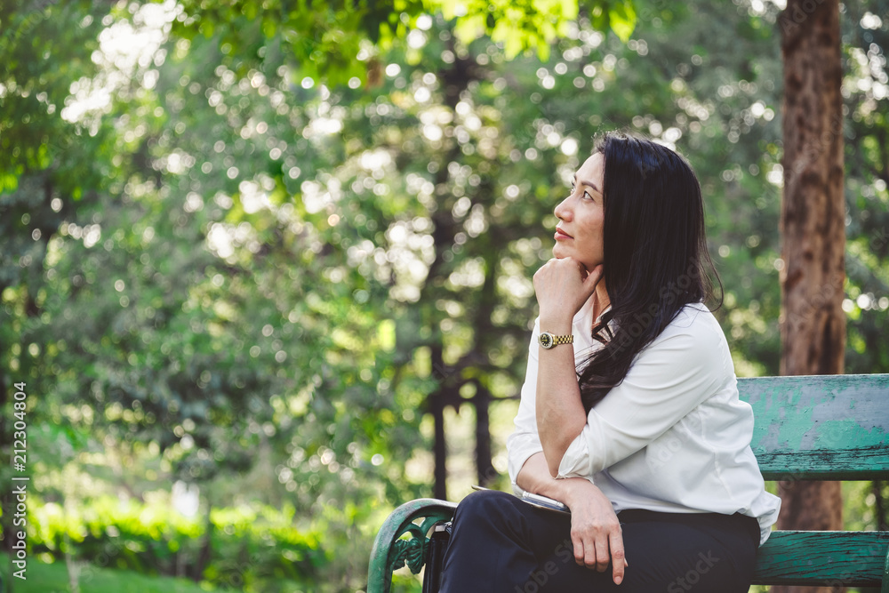 亚洲商业女性坐在带复制空间的户外公园里思考