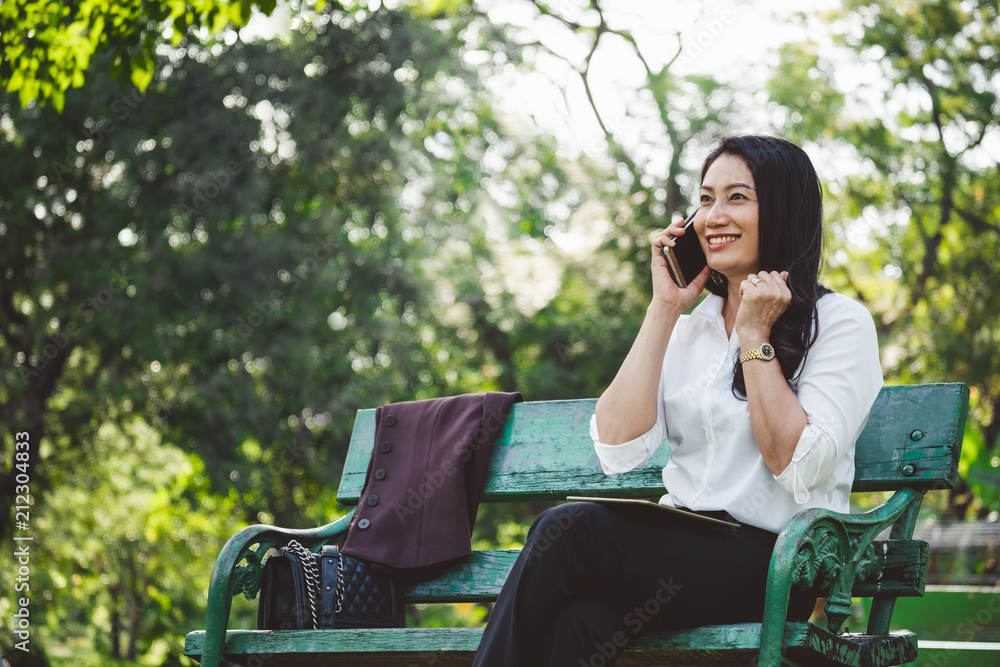 亚洲商界女性在公园户外打手机时有好消息