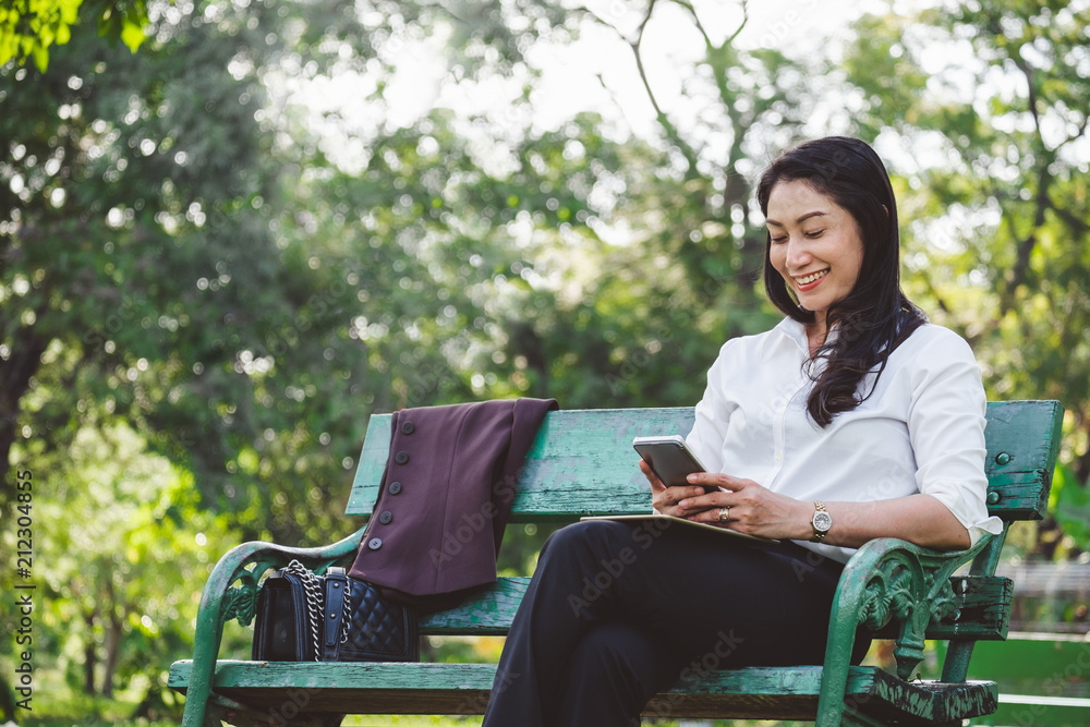 亚洲商界女性使用智能手机上网和互联网在公园户外工作