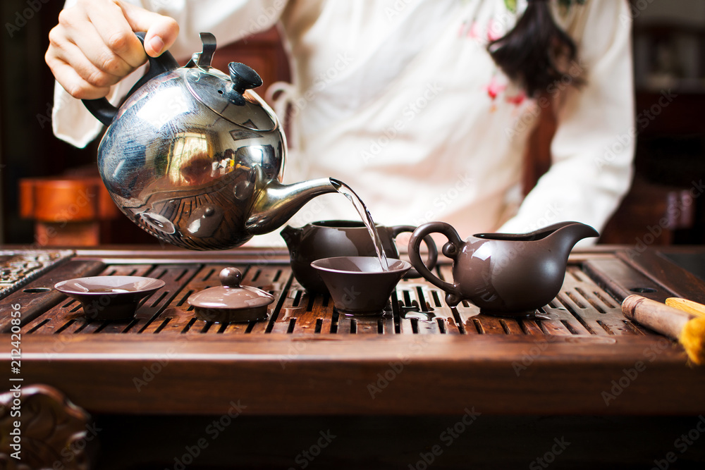 女人用开水清洗茶杯和茶壶，茶道