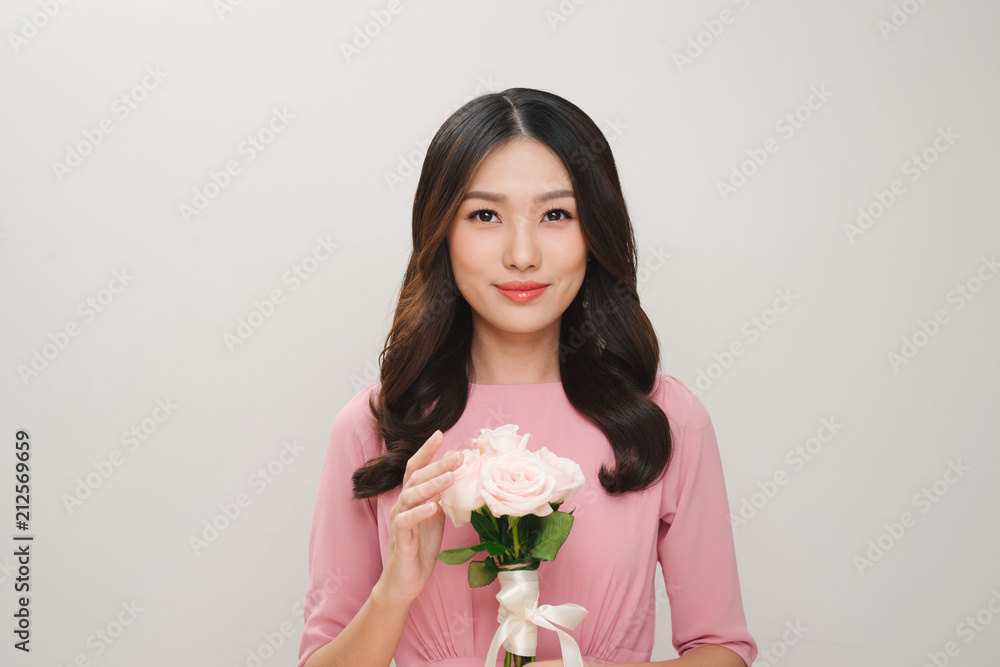 一位穿着粉色连衣裙的满意年轻女子的肖像，手里拿着一束被隔离的玫瑰