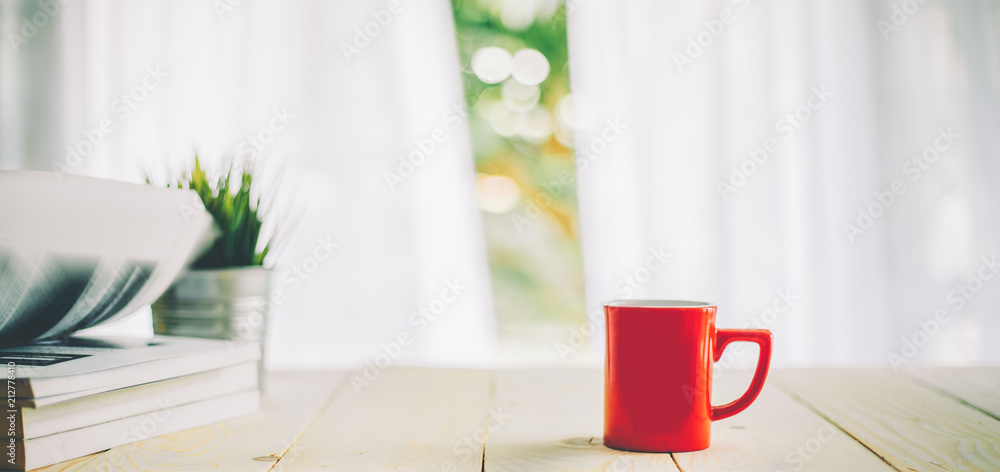 一杯咖啡放在木桌面上，窗帘模糊，背景为窗户