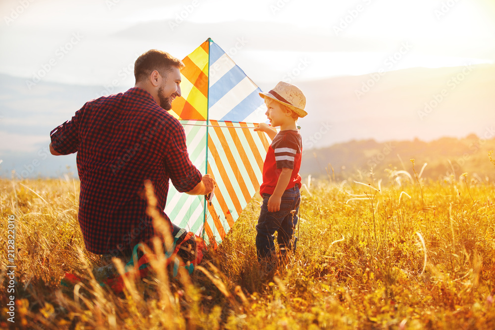 幸福家庭父亲和孩子儿子在草地上放风筝。