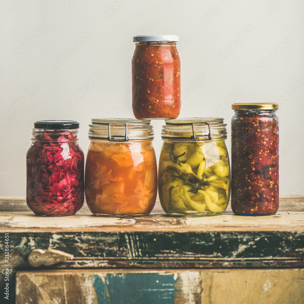 秋季时令腌制或发酵彩色蔬菜，装在老式厨房抽屉上的罐子里，白色