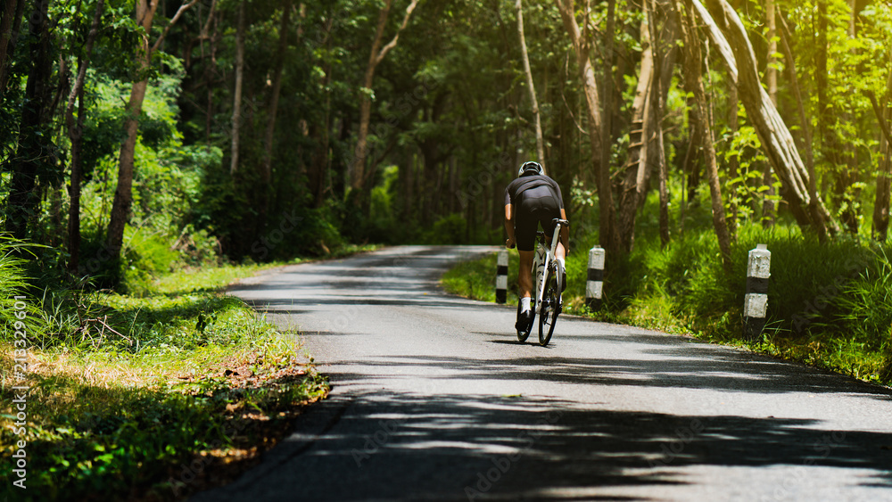 骑自行车的人他在树林里骑自行车上坡。