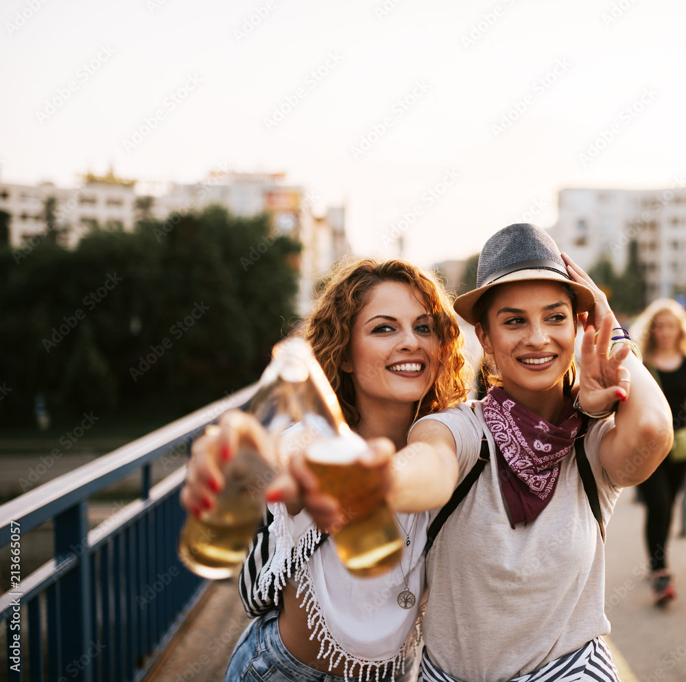两个派对女孩在夏天喝酒欢呼的画像。