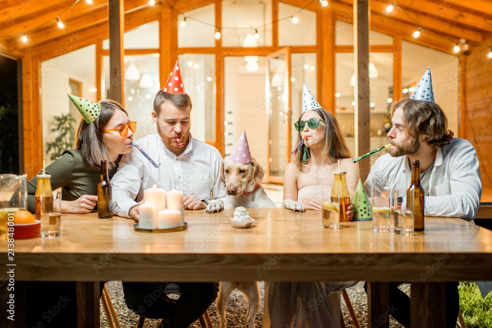 晚上，朋友们在后院的桌子上用蛋糕庆祝狗狗的生日