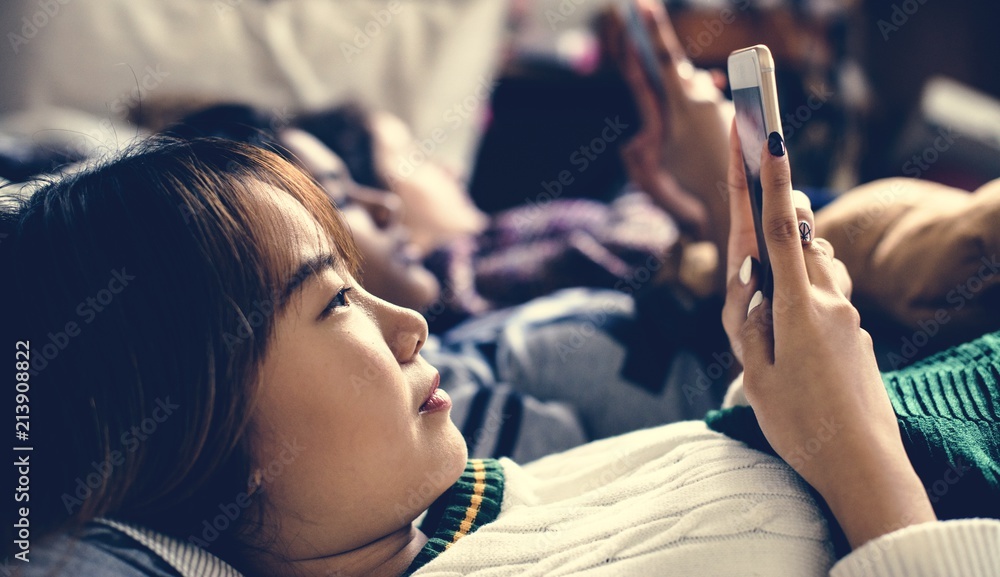 青少年女孩在睡眠派对中在床上上网使用智能手机