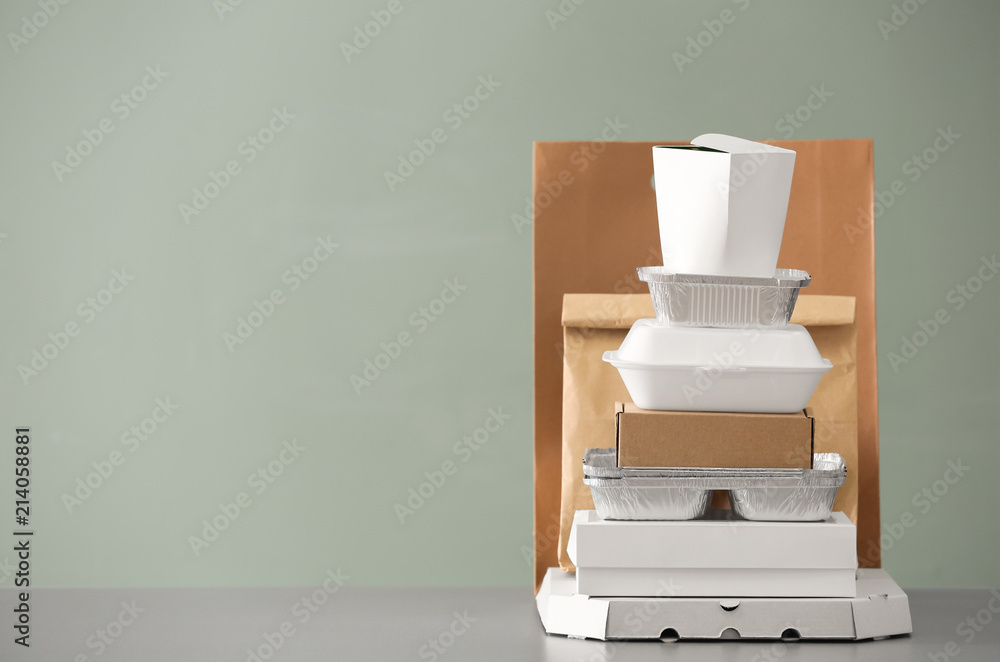Different packages on table against color background. Food delivery service