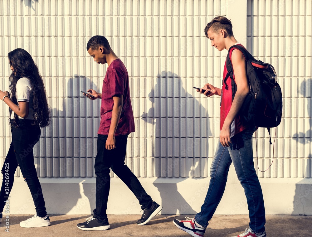一群年轻的青少年朋友放学回家时使用智能手机成瘾概念