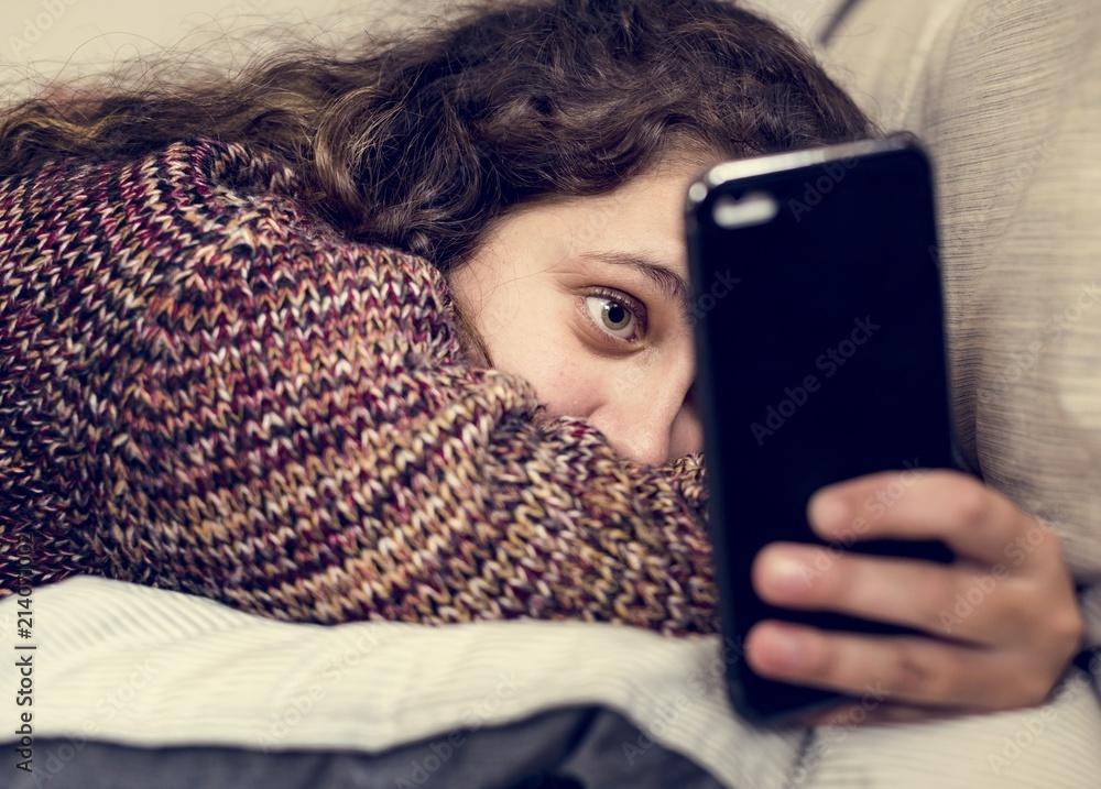 青少年女孩在床上使用智能手机社交媒体和成瘾概念