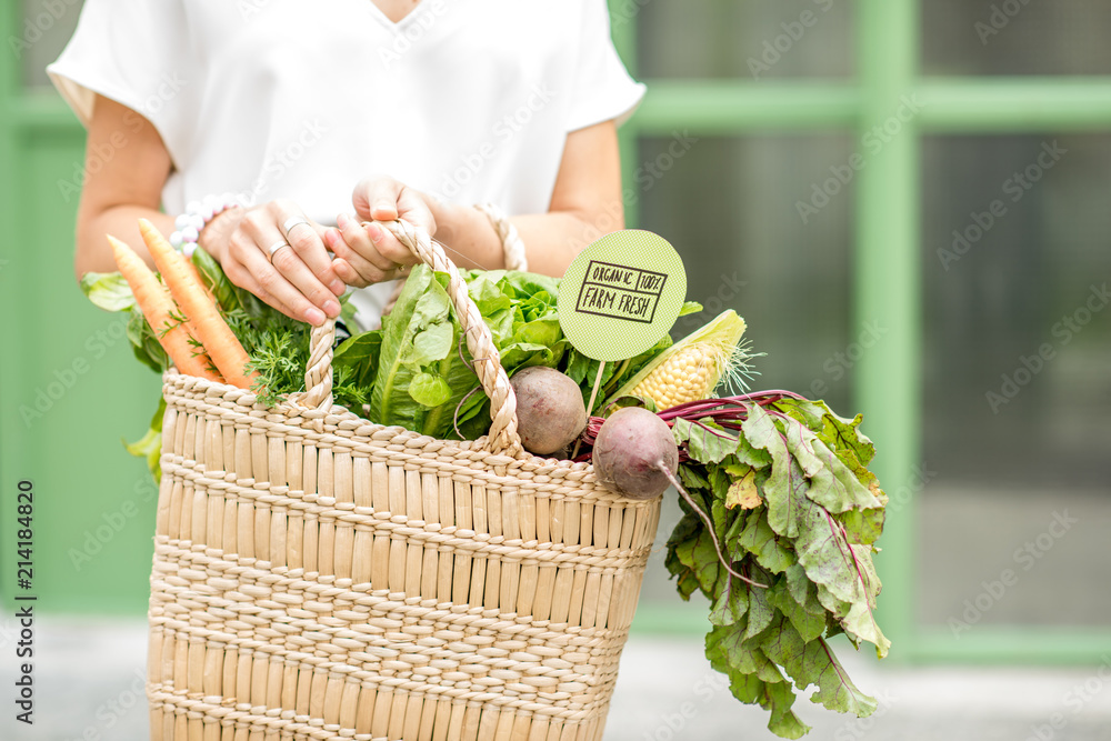 绿色背景下装满当地市场新鲜有机蔬菜的手提袋
