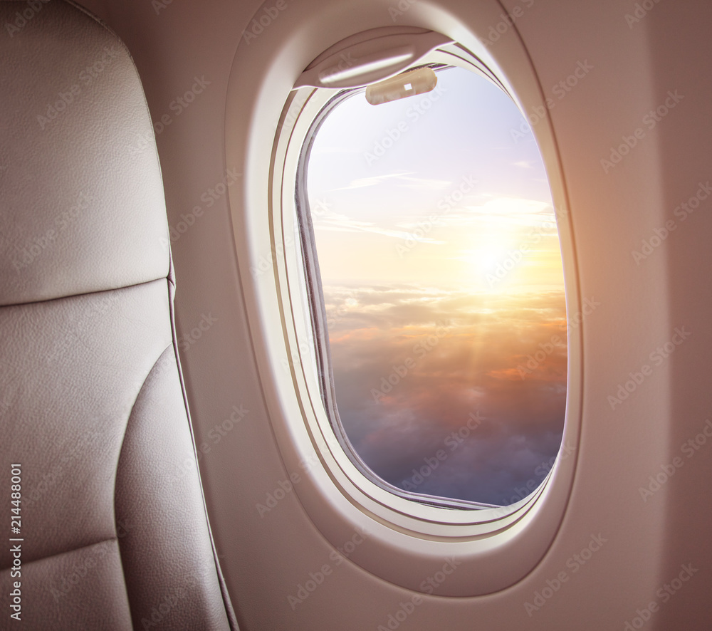 飞机内部，从窗户可以看到云层上方的日落。
