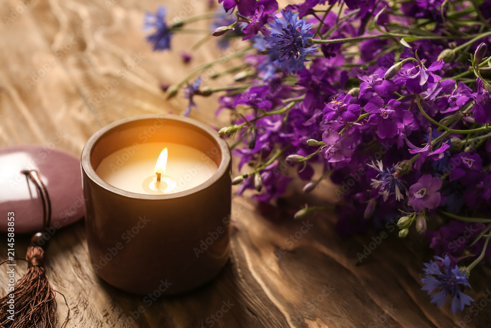 木桌上燃烧的蜡烛和美丽的花朵