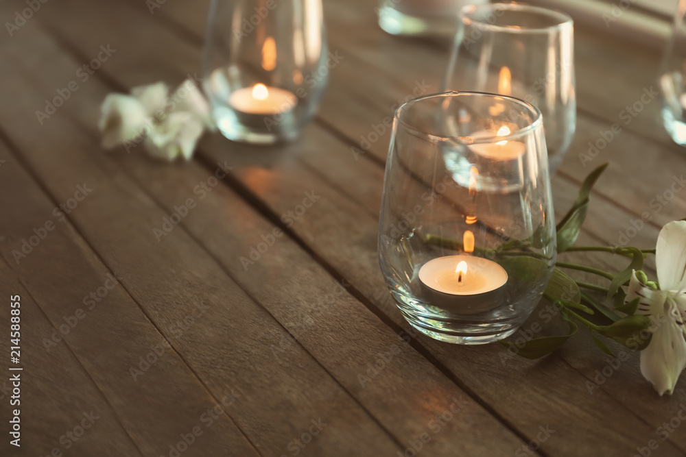 木桌上玻璃杯里燃烧的美丽蜡烛