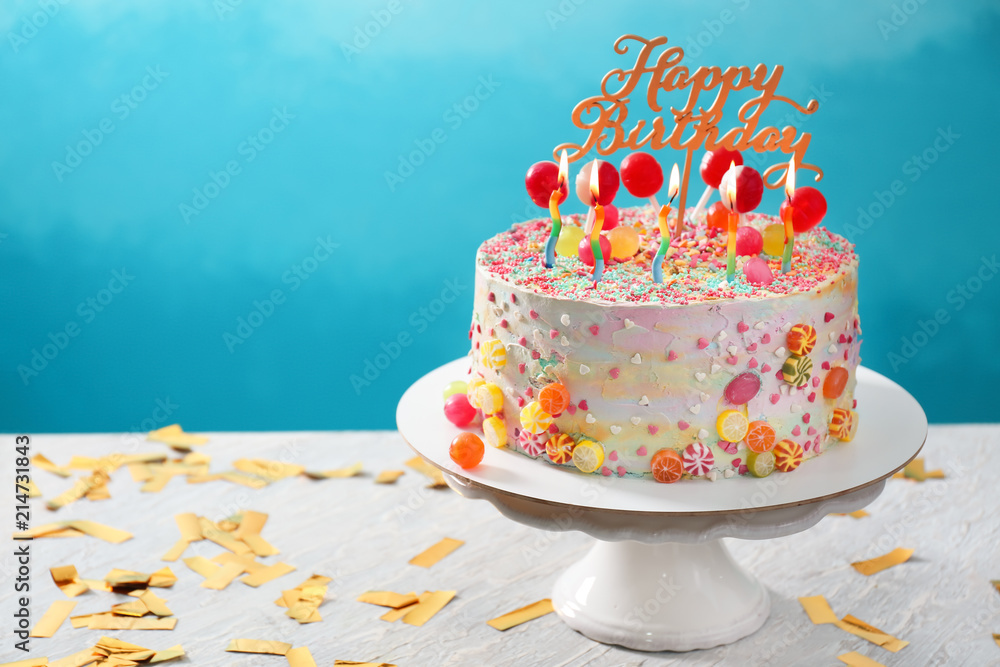 在彩色背景下，把美味的生日蛋糕放在桌子上