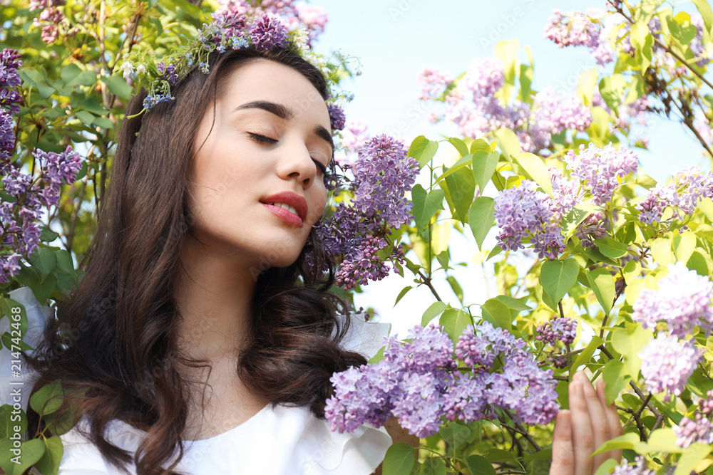 阳光明媚的春天，美丽的年轻女子在盛开的灌木旁戴着花环