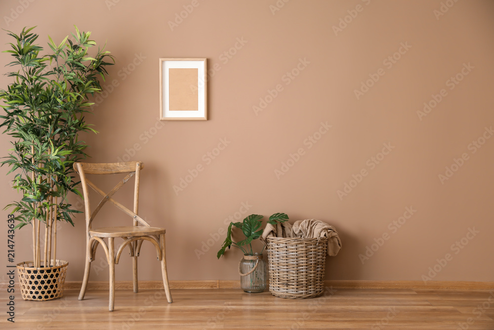 带柳条篮和靠近彩色墙的植物的木椅