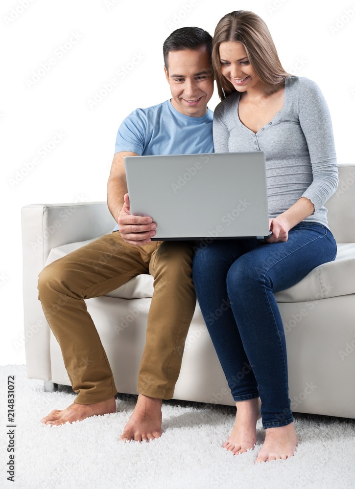微笑的情侣在沙发上使用笔记本电脑