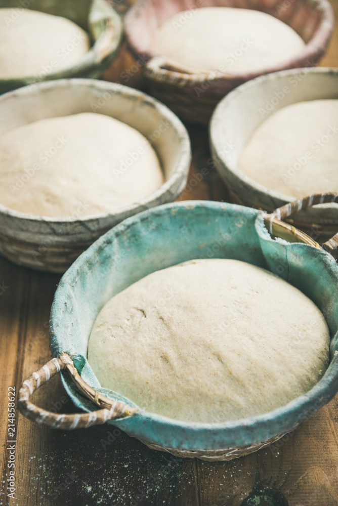 在乡村木制厨房餐桌背景上用篮子烘焙自制小麦粉面包的Sourdough