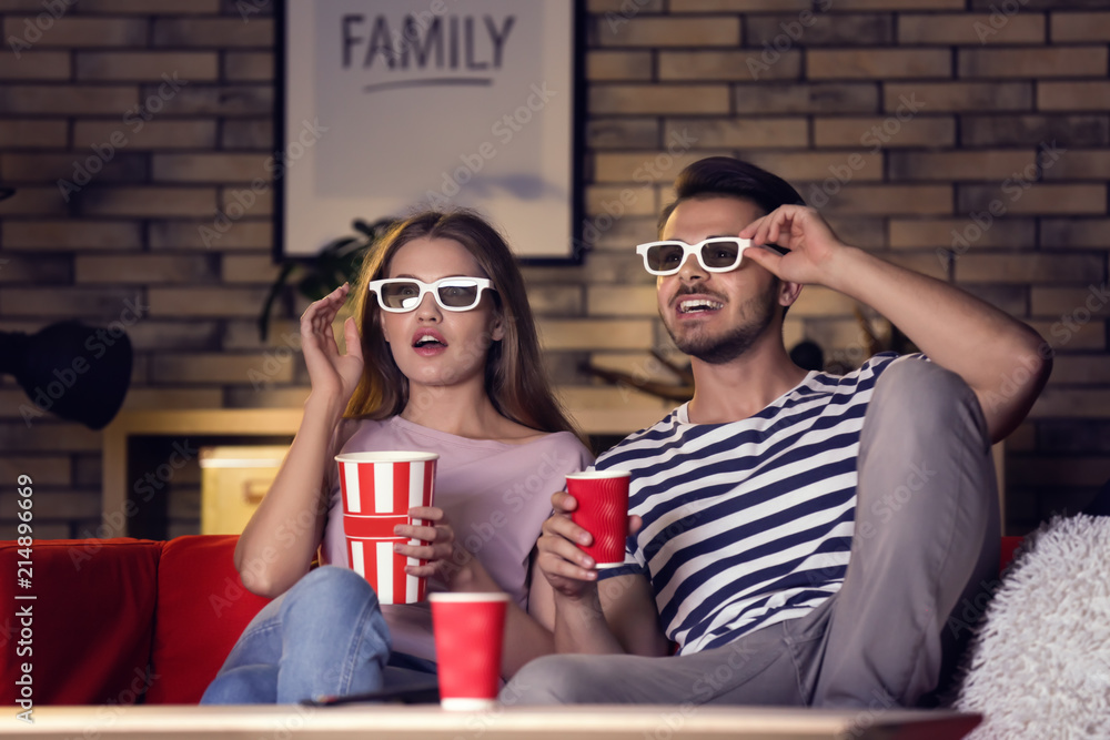 戴着3d眼镜的年轻夫妇晚上在沙发上看电影