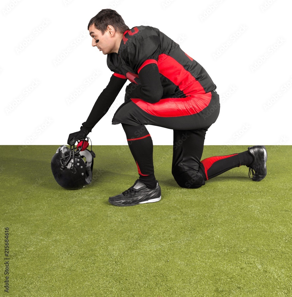 摘掉头盔跪在草地上的美国足球运动员