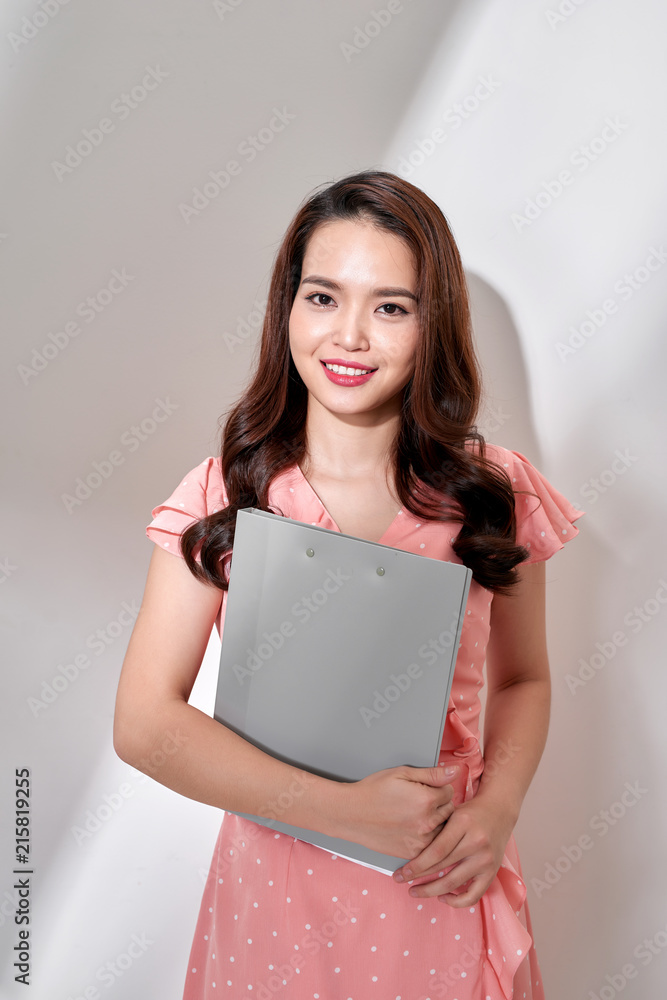Beautiful woman in pink dress with clipboard on white background