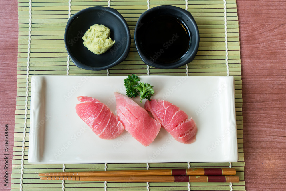 黑盘子里的Otoro金枪鱼寿司，配日本酱汁和绿叶装饰，日本食物，