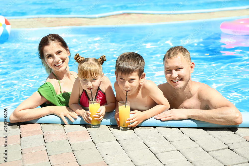 快乐的一家人，在游泳池里喝着几杯果汁休息
