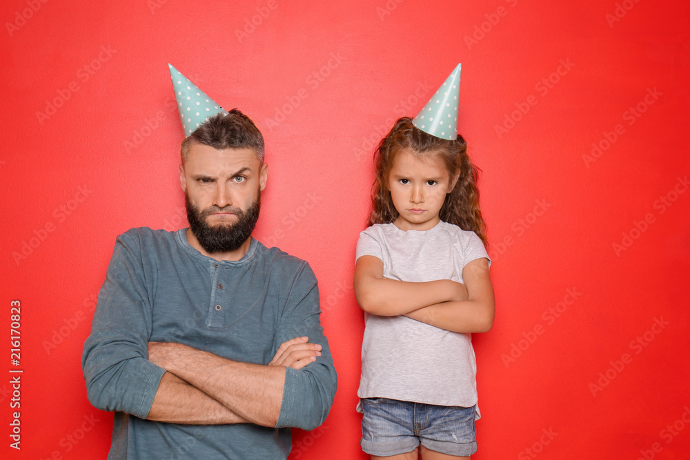 Portrait of father and his little daughter with party hats on color background