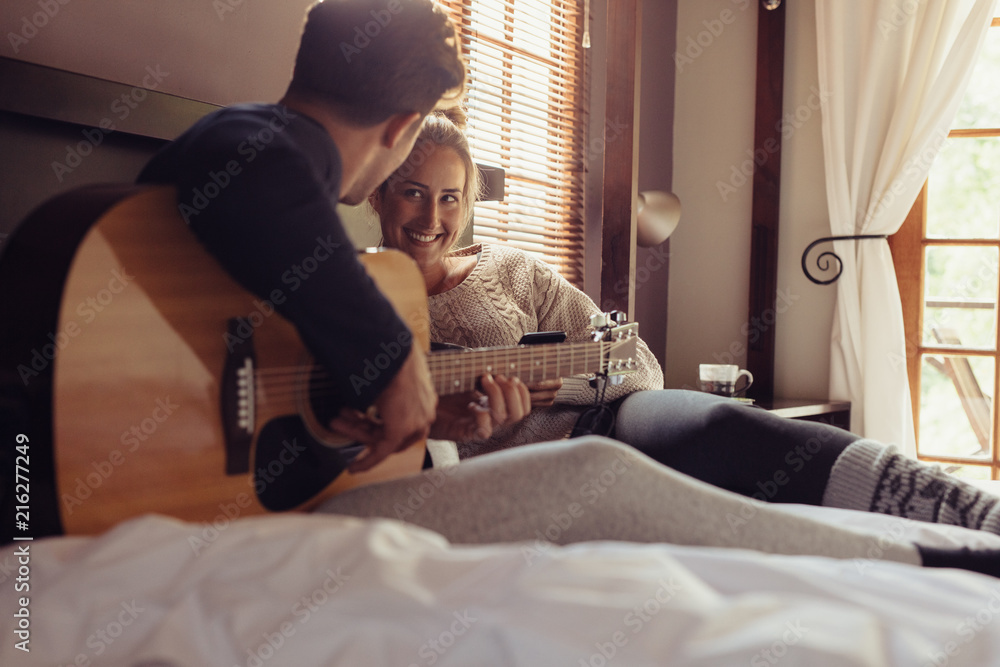 男子在床上为女友弹吉他