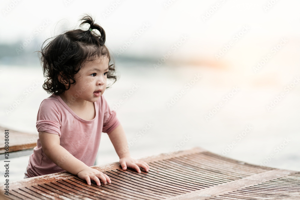 亚洲女孩在游泳池附近的木长椅上微笑着放松